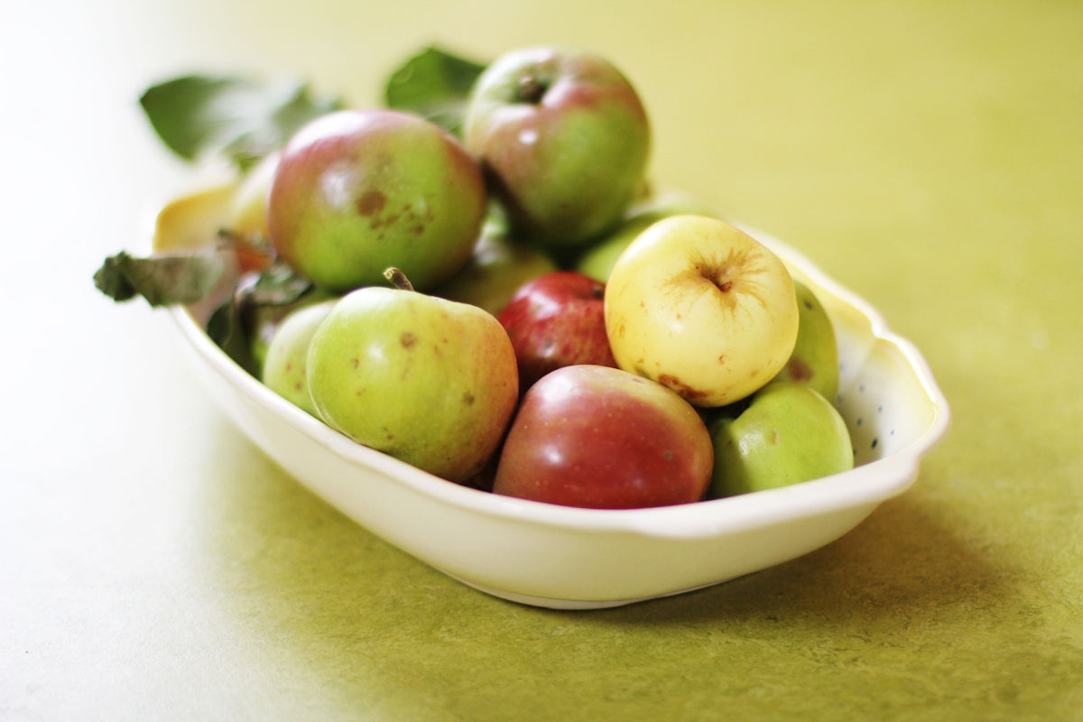 green and red apples in white ceramic bowl