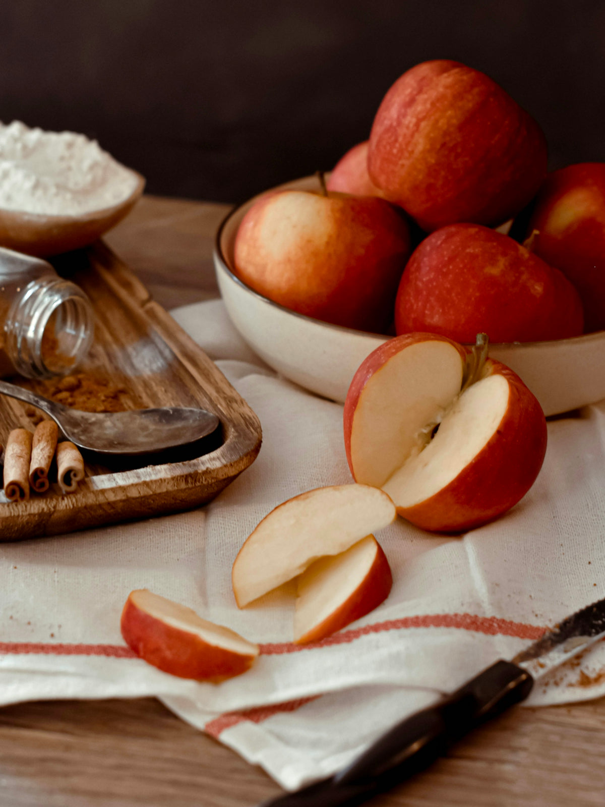 a wooden cutting board topped with apples next to a bowl of oatmeal