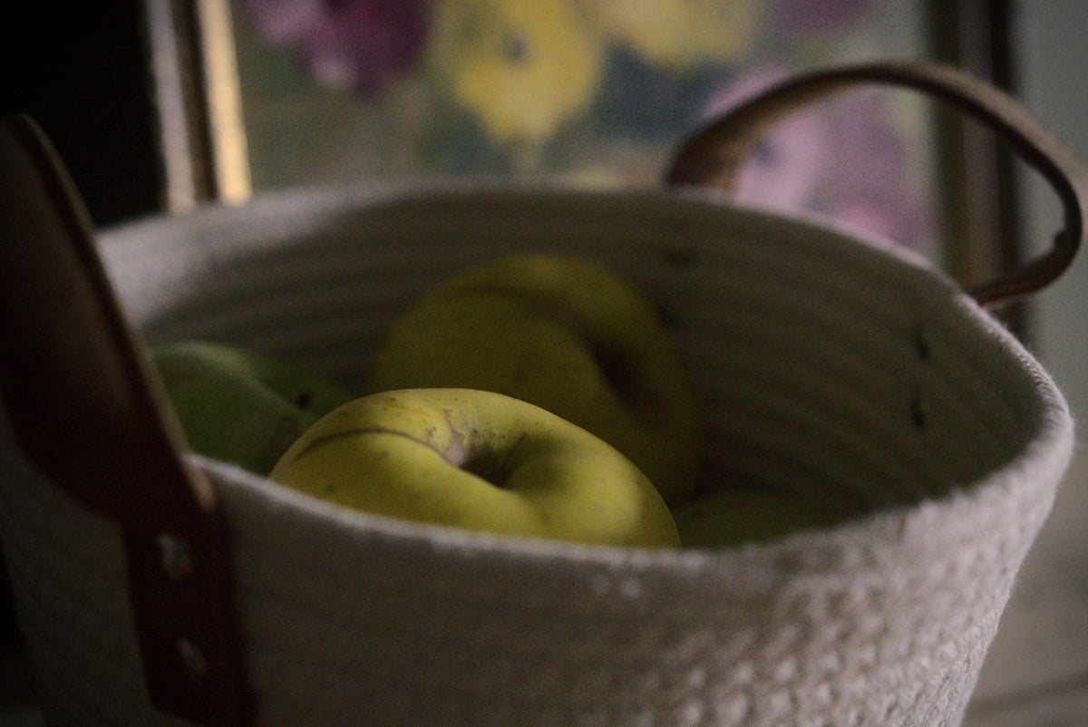a basket filled with green apples sitting on top of a table