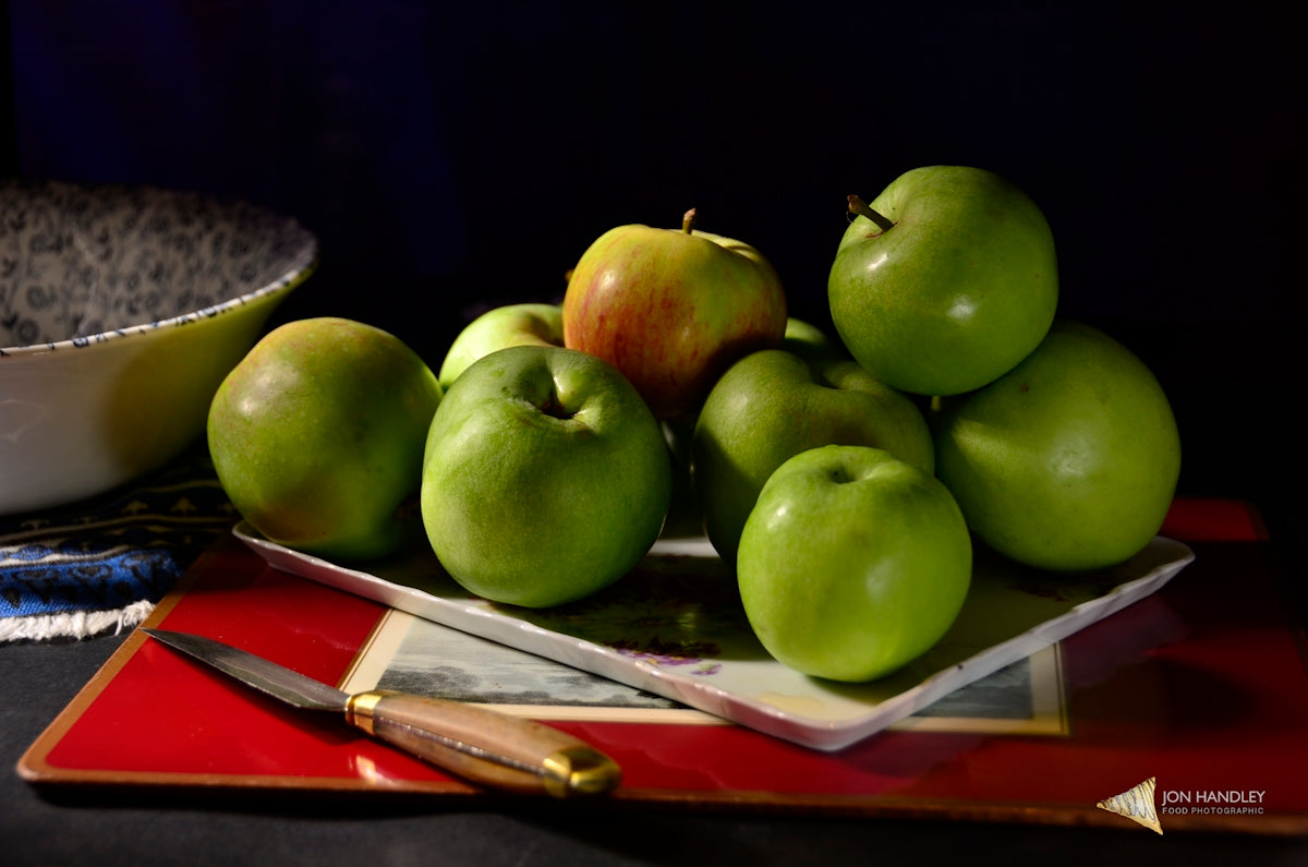 a pile of green apples sitting on top of a plate