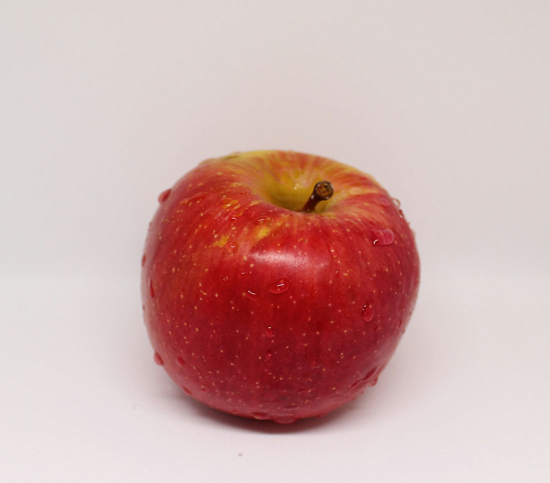 a red apple sitting on top of a white table