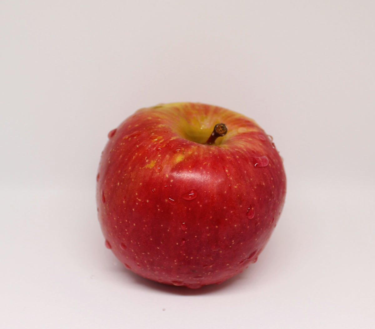 a red apple sitting on top of a white table