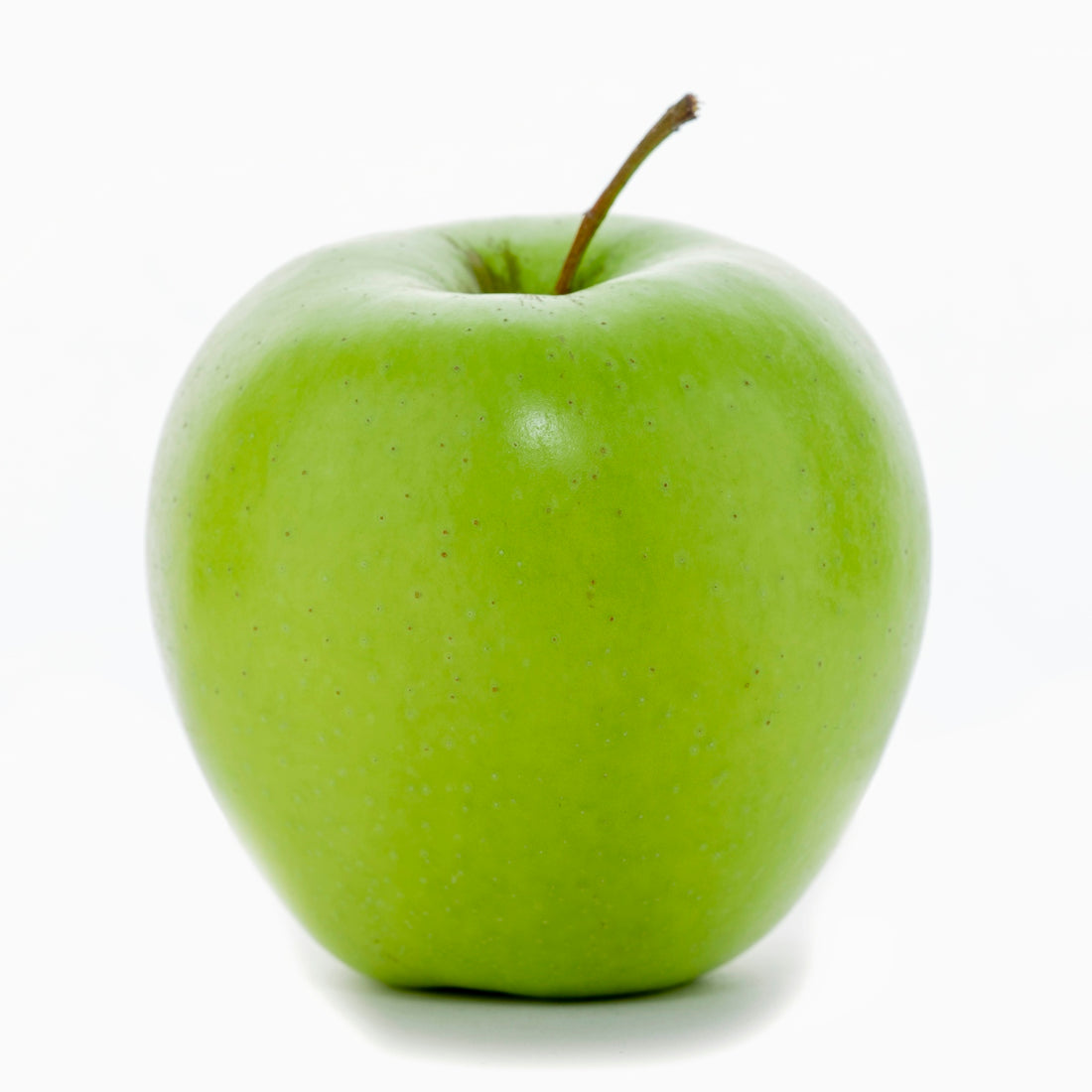 a green apple sitting on top of a white table