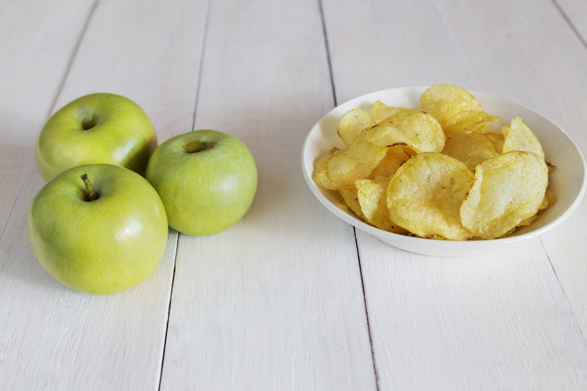 a bowl of chips next to a bowl of apples