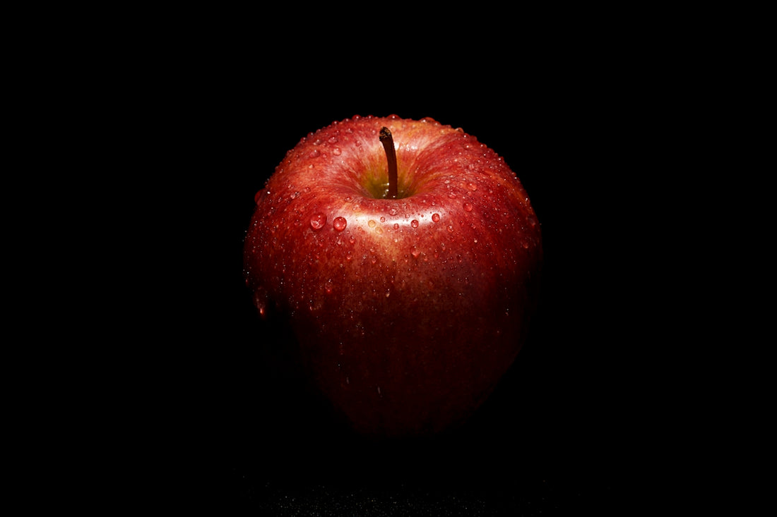 a red apple sitting on top of a black table