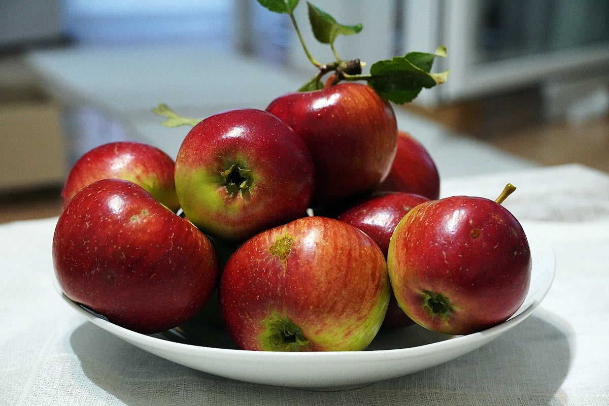 a white bowl filled with red apples on top of a table