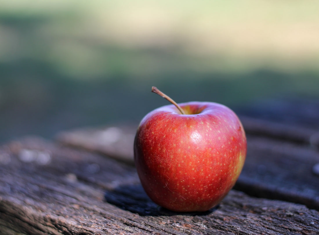 a red apple sitting on top of a wooden table