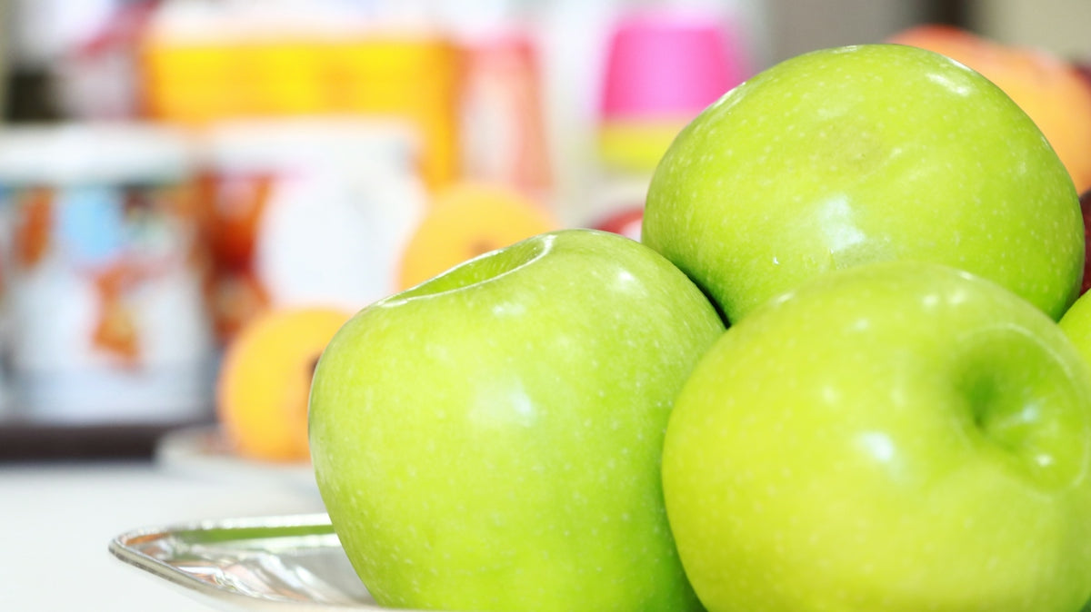 A pile of green apples sitting on top of a table