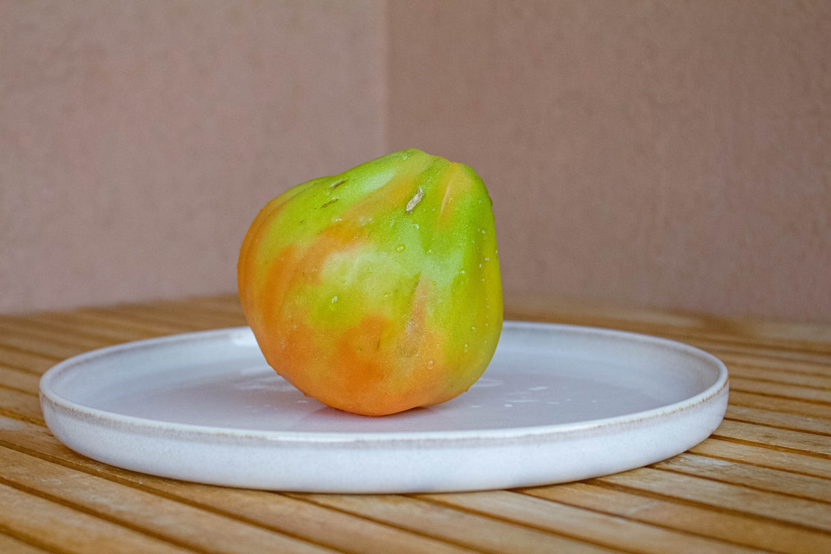 An apple sitting on a plate on a wooden table
