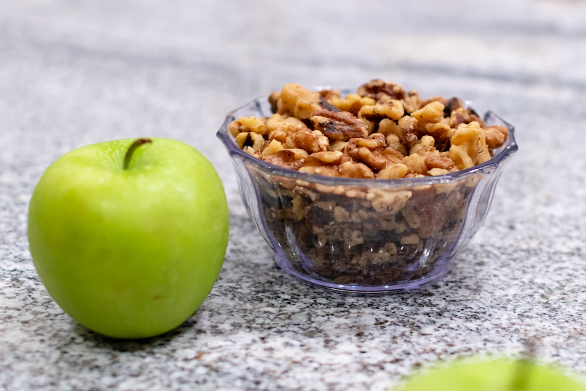 A bowl of granola next to an apple