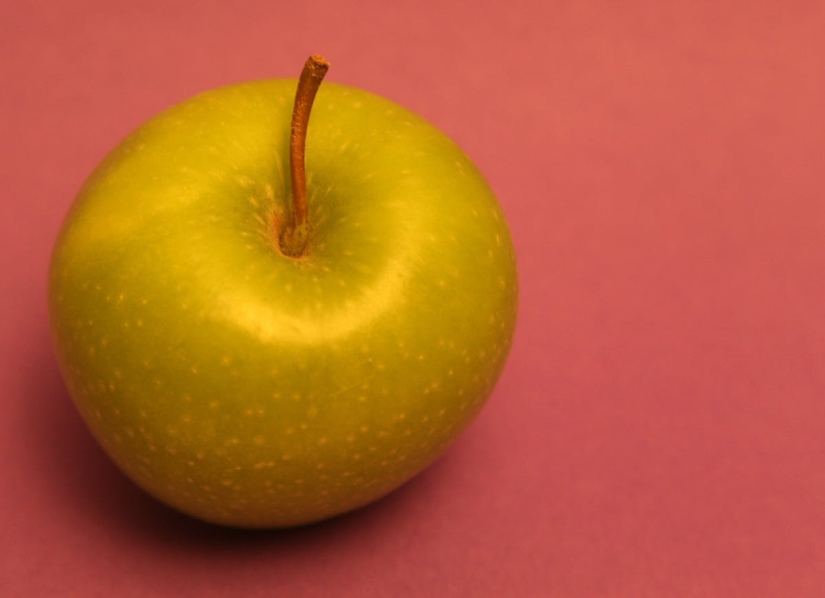 A green apple on a pink background.