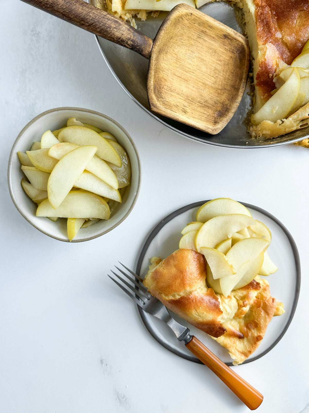 Dutch baby pancake with sliced apples in a bowl.