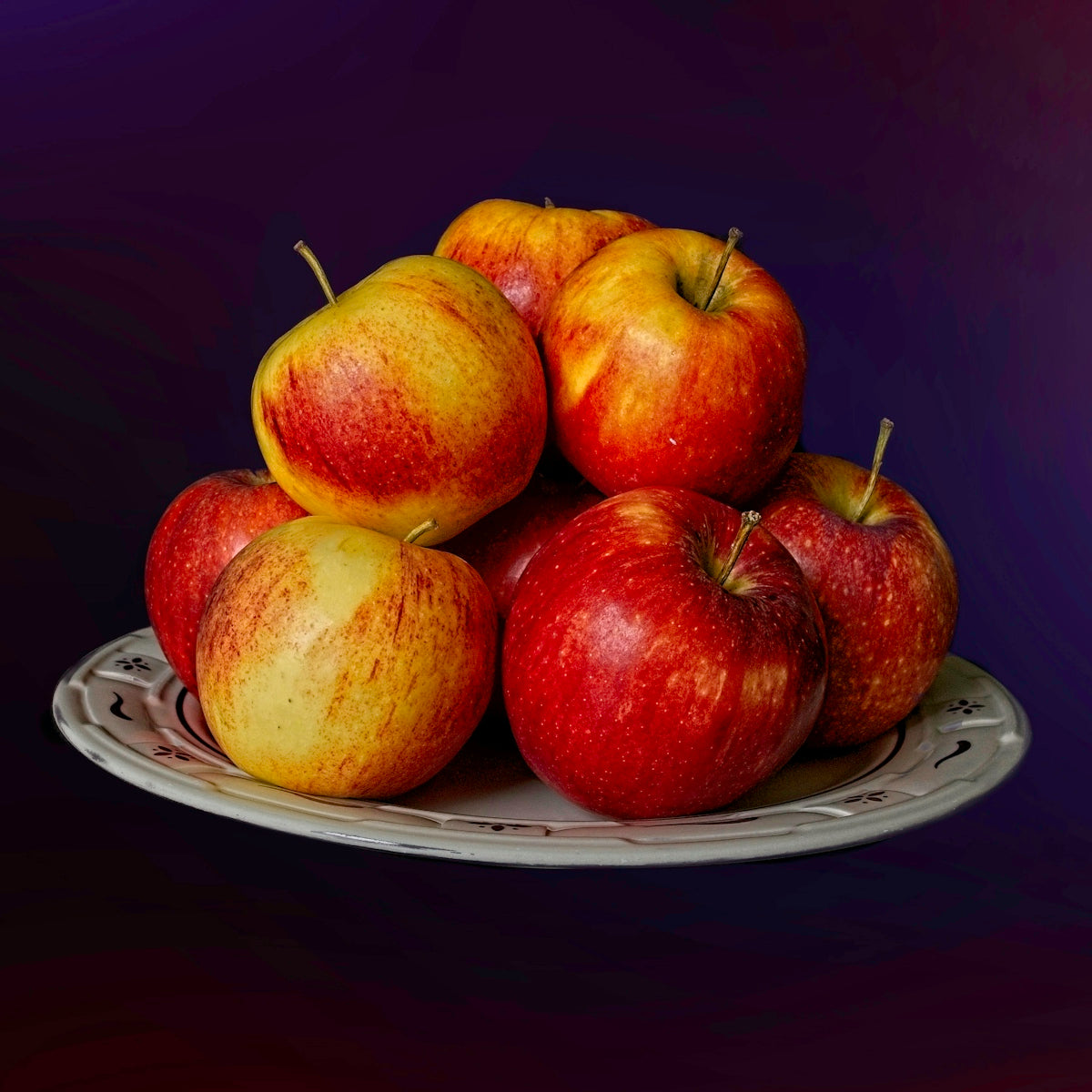 A pile of red and yellow apples on a plate